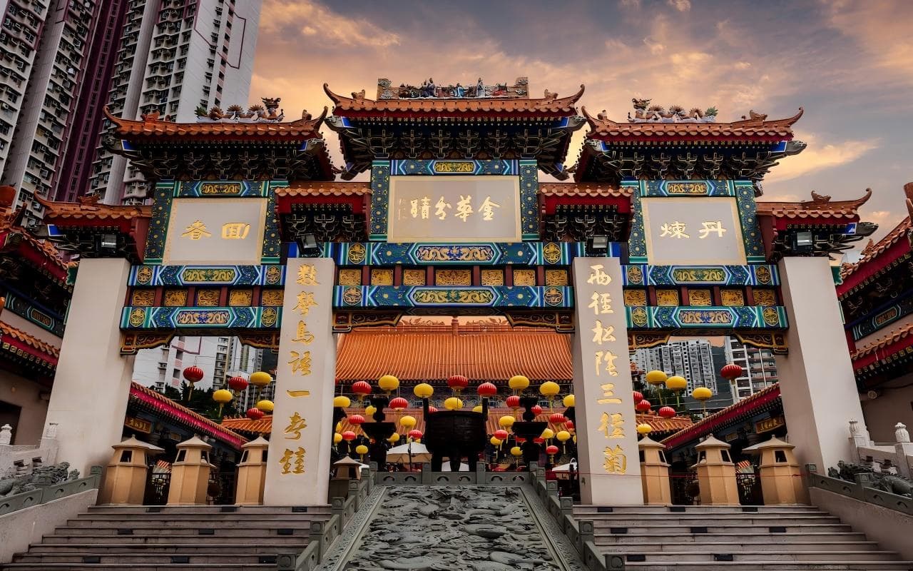 香港嗇色園黃大仙祠牌坊，牌坊上可見金華分蹟與嗇色園題字，背景為住宅樓宇